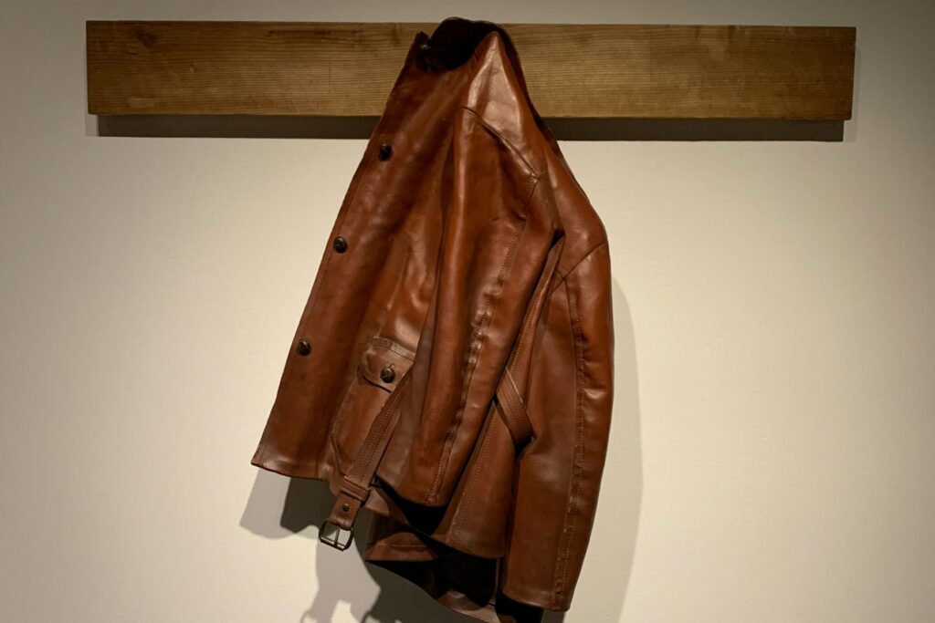 Brown leather jacket hanging on a wooden wall hook